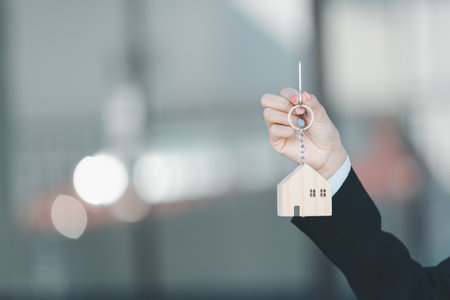 Woman hand hold key buy home model business concept involves sell financial management investment...