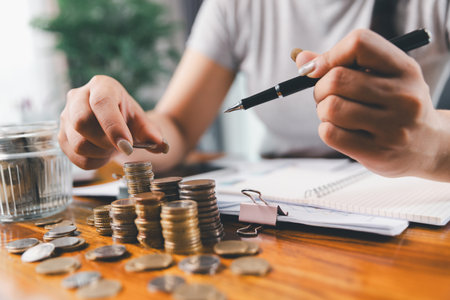 Businesswoman saving money with piggy bank and coins on desk, financial planning and investment concept. Young Asian woman making stack of coin. invest save finance, saving money, investmentの写真素材