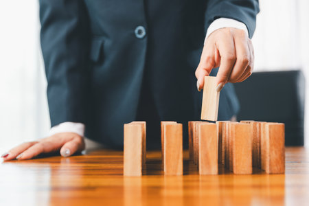 Business risk control concept, Businesswoman protect wooden block fall to planning and strategy in risk to business alternative and prevent. investment insurance business.の写真素材