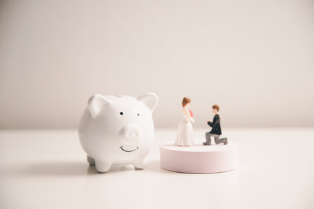 Save money for wedding and planning wedding concept. Sustainable financial goal for family life or married life. Miniature wedding on rows of rising coins, depicts savings or growth for new family.の写真素材