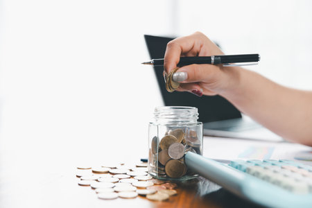 Businesswoman saving money with piggy bank and coins on desk, financial planning and investment concept. Young Asian woman making stack of coin. invest save finance, saving money, investmentの写真素材