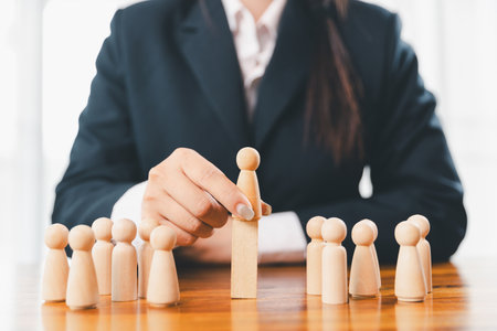 Hands protecting family wooden model for insurance and assurance life concept. Businessman hand gesture protecting wooden domino falling to family dolls for insurance and assurance.の写真素材