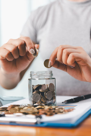 Businesswoman saving money with piggy bank and coins on desk, financial planning and investment concept. Young Asian woman making stack of coin. invest save finance, saving money, investmentの写真素材