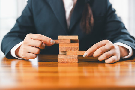 Business risk control concept, Businesswoman protect wooden block fall to planning and strategy in risk to business alternative and prevent. investment insurance business.の写真素材