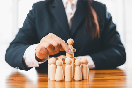 Hands protecting family wooden model for insurance and assurance life concept. Businessman hand gesture protecting wooden domino falling to family dolls for insurance and assurance.の写真素材