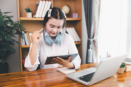 Asian girl student wear headphones learning online watching webinar class looking at laptop computer...