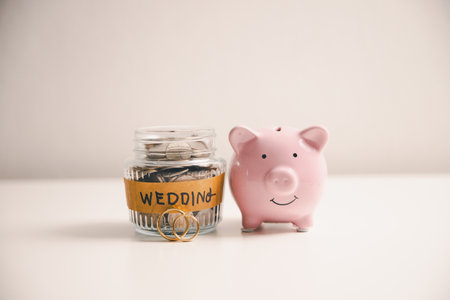 Save money for wedding and planning wedding concept. Sustainable financial goal for family life or married life. Miniature wedding on rows of rising coins, depicts savings or growth for new family.の写真素材