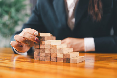 Business risk control concept, Businesswoman protect wooden block fall to planning and strategy in risk to business alternative and prevent. investment insurance business.の写真素材