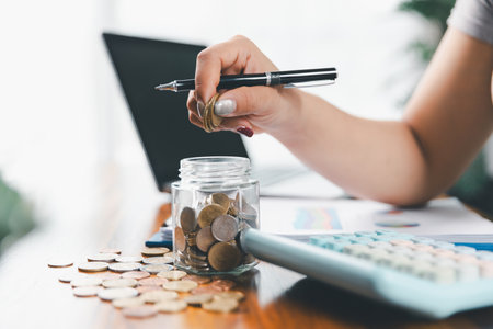Businesswoman saving money with piggy bank and coins on desk, financial planning and investment concept. Young Asian woman making stack of coin. invest save finance, saving money, investmentの写真素材