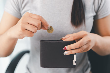 Young Asian woman making stack of coin. invest save finance concept, saving money, investment. dollar bills on table with pile of coins and calculator, money to save and invest to make income.の写真素材