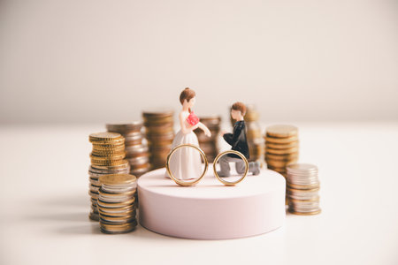 Save money for wedding and planning wedding concept. Sustainable financial goal for family life or married life. Miniature wedding on rows of rising coins, depicts savings or growth for new family.の写真素材