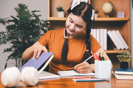 woman sitting at desk working on laptop taking notes in notebook, female studying online, watching webinar using computer, writing check list. Remote college school education, e learning concept.の写真素材