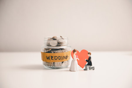 Save money for wedding and planning wedding concept. Sustainable financial goal for family life or married life. Miniature wedding on rows of rising coins, depicts savings or growth for new family.の写真素材