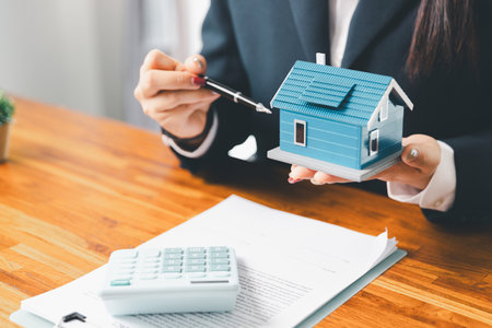 Home loan officer uses calculator with house plan loan real estate or property. important to loan calculator seek real estate, finance insurance advice ensure smart financial decisions for business.の写真素材
