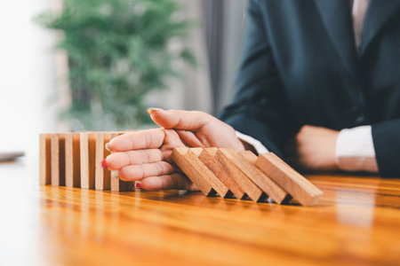 Business risk control concept, Businesswoman protect wooden block fall to planning and strategy in risk to business alternative and prevent. investment insurance business.の写真素材