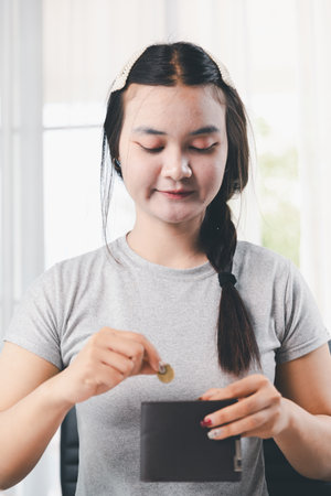 Young Asian woman making stack of coin. invest save finance concept, saving money, investment. dollar bills on table with pile of coins and calculator, money to save and invest to make income.の写真素材