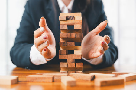 Business risk control concept, Businesswoman protect wooden block fall to planning and strategy in risk to business alternative and prevent. investment insurance business.の写真素材