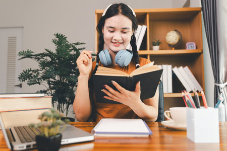 woman sitting at desk working on laptop taking notes in notebook, female studying online, watching webinar using computer, writing check list. Remote college school education, e learning concept.の写真素材