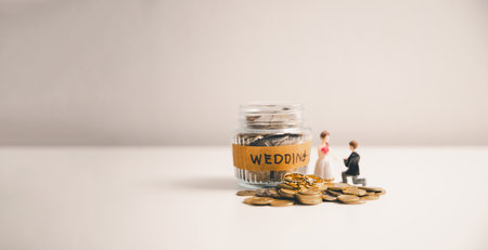 Save money for wedding and planning wedding concept. Sustainable financial goal for family life or married life. Miniature wedding on rows of rising coins, depicts savings or growth for new family.の写真素材