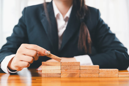 Business risk control concept, Businesswoman protect wooden block fall to planning and strategy in risk to business alternative and prevent. investment insurance business.の写真素材