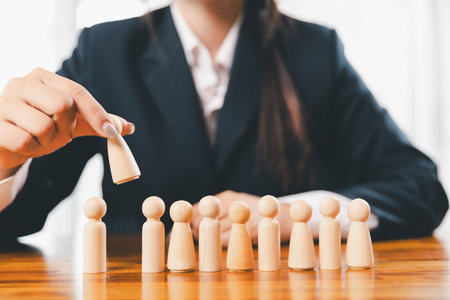Hands protecting family wooden model for insurance and assurance life concept. Businessman hand gesture protecting wooden domino falling to family dolls for insurance and assurance.の写真素材