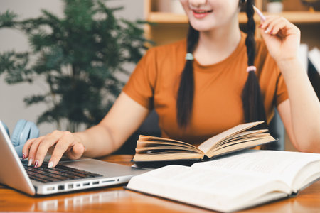 woman sitting at desk working on laptop taking notes in notebook, female studying online, watching webinar using computer, writing check list. Remote college school education, e learning concept.の写真素材