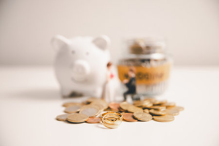 Save money for wedding and planning wedding concept. Sustainable financial goal for family life or married life. Miniature wedding on rows of rising coins, depicts savings or growth for new family.の写真素材
