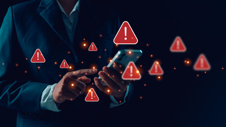 Person using phone and laptop is shown online with red warning signs indicating potential security threats. Cybersecurity technology, system warning on hacked alerts. System warning error popup.の写真素材