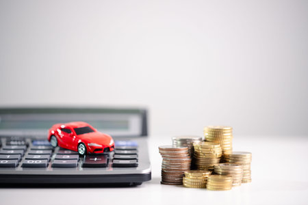 Auto loan budgeting and purchase cost planning concept for smart personal finance and savings with copy space on white background, ending with red toy car on calculator and stacks of coins. budgetingの写真素材