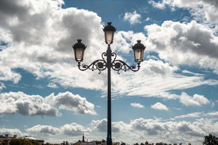 Photography of the streetlight located on the Isabel II bridge, Triana bridge in Seville, with a background of cloudsの写真素材