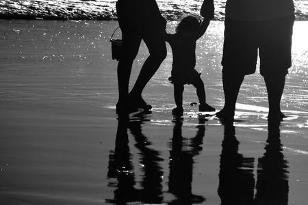 Young family on vacation at the beach. Kids first steps with her family at Santa Monica beach. black and white.の写真素材