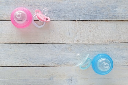 Pink and Blue pacifiers and baby bootles representing both girl and boy. Empty space for editor's...