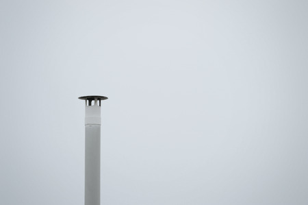 A smokestack against a grey sky. Empty copy space for editor's text.