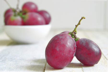 Some grapes on a white wooden table of a rustic kitchen. Empty copy space for editor's text.の写真素材