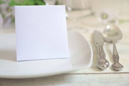 Invitation card on a decorated table with classic cutlery and some flowers.の写真素材