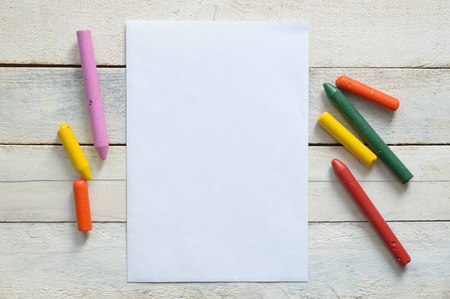 Paper and some crayons on a wooden table in a classroom. Empty copy space for Editor's text.の写真素材