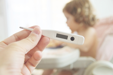 A hand holding a thermometer. Children care.