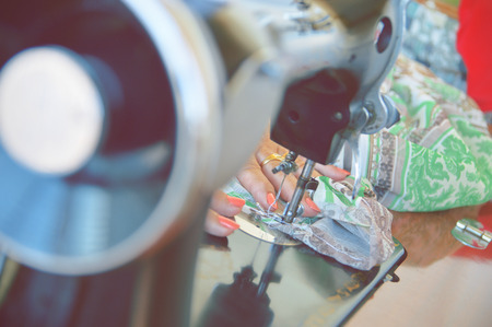 Hands of a woman working in a sewing workshop with an old sewing-machine. Some colorful fabric.の写真素材
