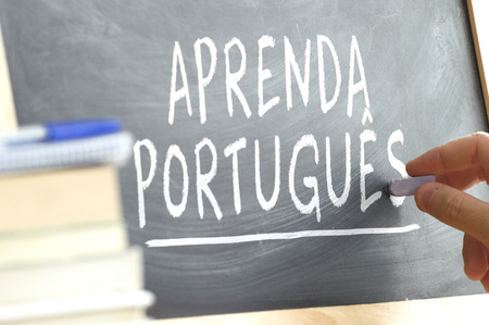 Hand writing on a blackboard in a Portuguese class. Some books and school materials.の写真素材