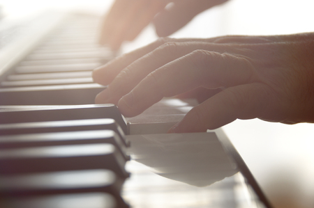 Hands playing piano Against a sunlight lighting at a music lesson in a class.の写真素材