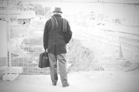 Old man holding a briefcase wearing a hat. Retirement metaphor. Empty copy space for Editor's text.の写真素材