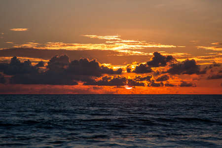 Beautiful clouds and the sun behind them over the seaの写真素材