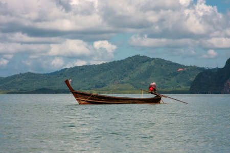 Boat in the sea on the background of a rocky shore