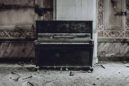 An antique black piano stands in an abandoned manor house. Shabby walls. Remains of a beautiful interiorの写真素材