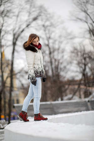 beautiful girl stands under the falling snowの写真素材