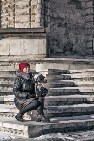 A girl and a dog are sitting on the steps of an old stone staircaseの写真素材