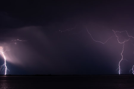 Lightning strikes at night over a huge riverの写真素材