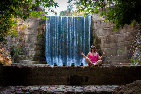 girl meditates on the background of a waterfallの写真素材