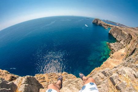 guy sits on the edge of a high cliffの写真素材
