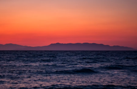 mountains and sea on a background of red sunsetの写真素材
